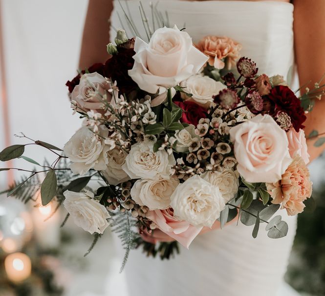 Bride holds floral bouquet complete with neutral colours and deep tones