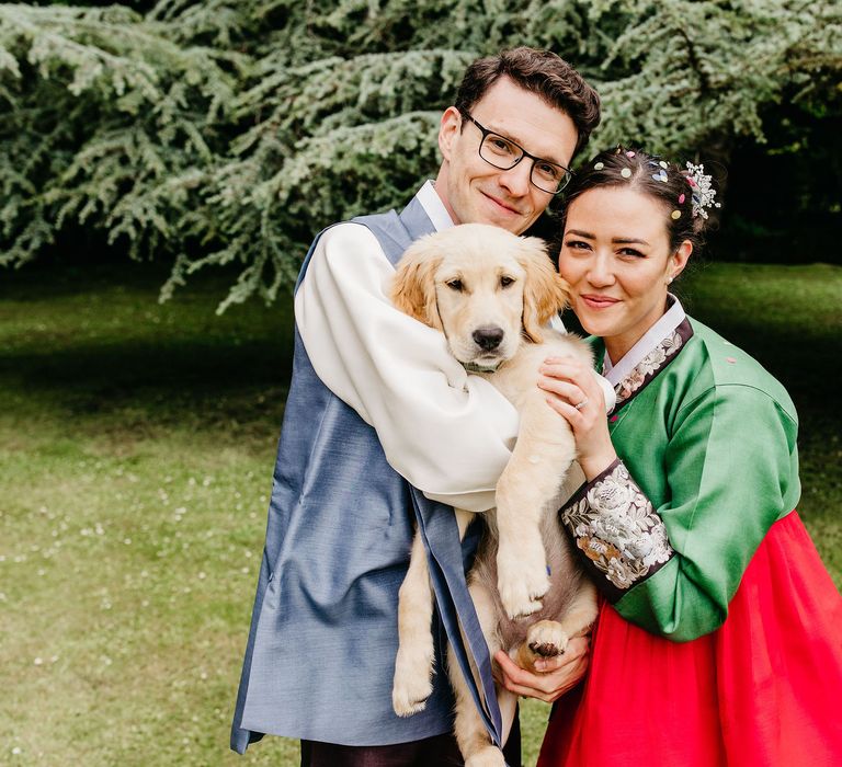 Bride & groom hug their puppy on their wedding day 