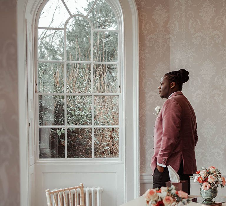 Groom looks out the window on his wedding day