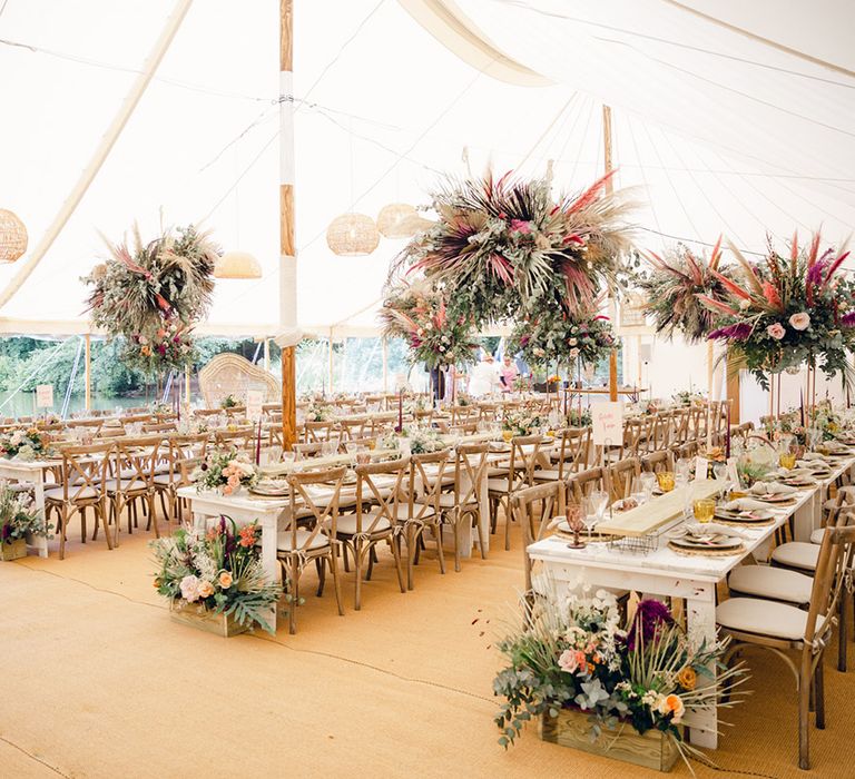 Marquee wedding with gorgeous flower decor hanging above the long wooden tables