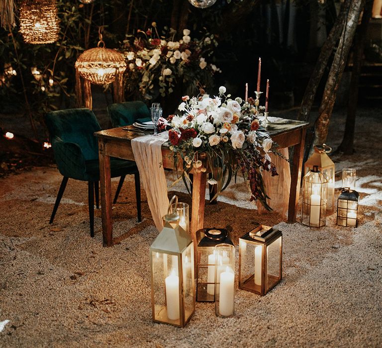 Top table area with pink candles and plush green velvet chairs and candle lanterns with disco balls overhead