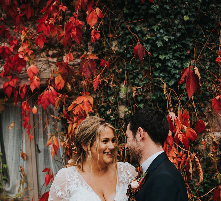 Bride in a plunging neck wedding dress and groom in a navy suit wedding portrait at Askham Hall in the autumn 