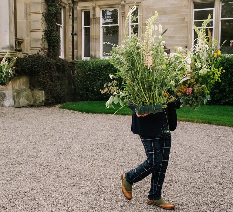 Wedding preparations with guests in traditional tartan outfits get the wedding flowers into place