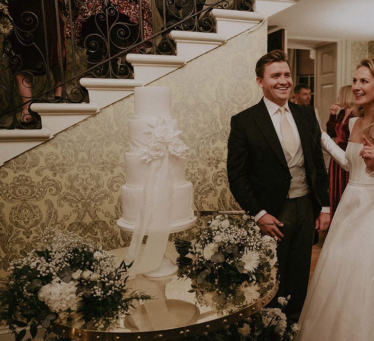 Bride and groom with semi-naked white wedding cake at Hedsor House wedding