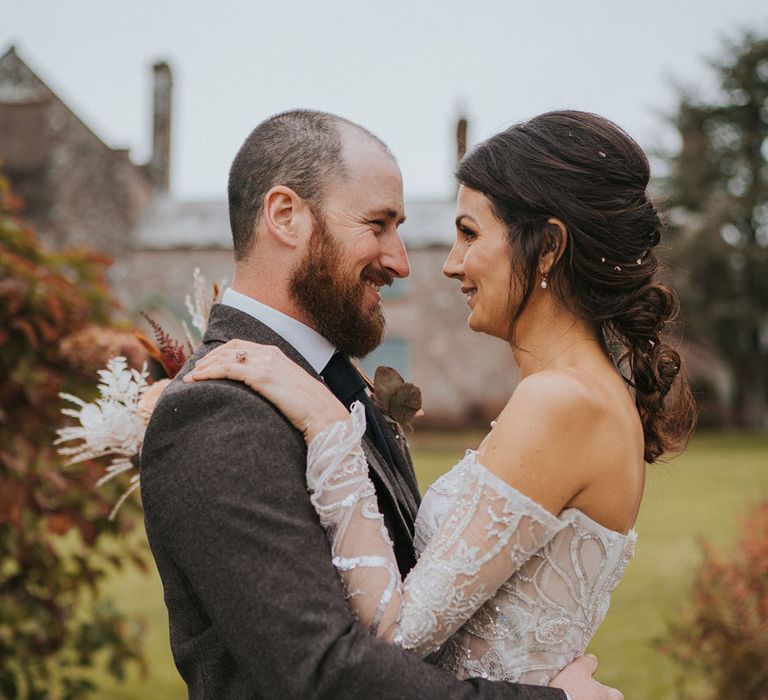 Bride and groom hug close together and look closely into each other's eyes