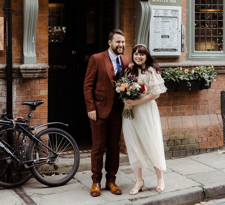 Bride and groom smile and pose outside of their wedding breakfast venue, Minster Inn in York