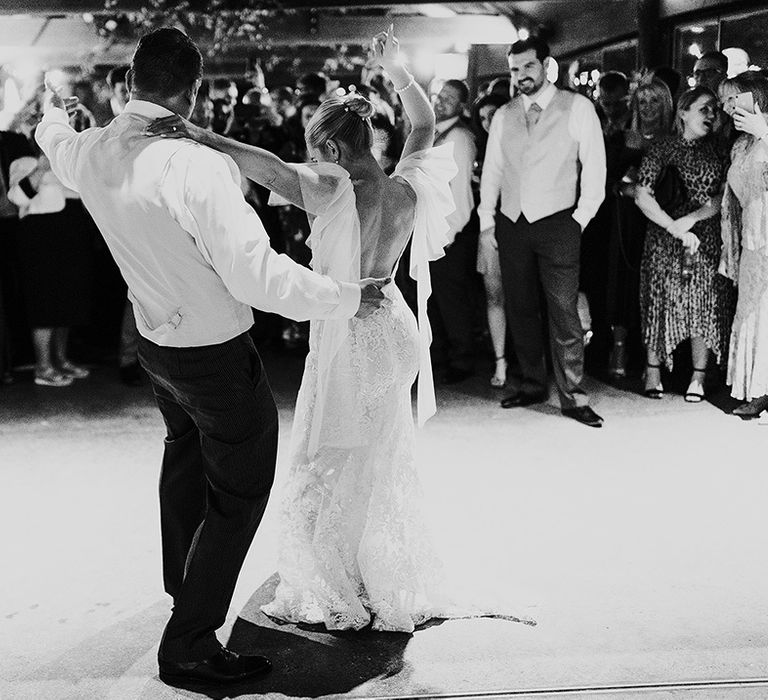 Bride and groom have their first dance as wedding guests look on 