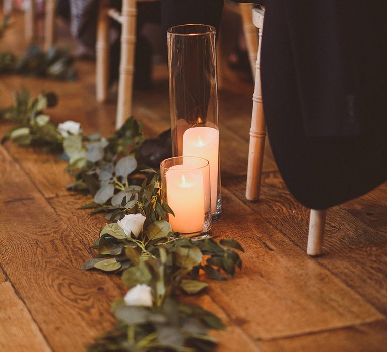 Green foliage, white rose and pillar candle aisle decoration 