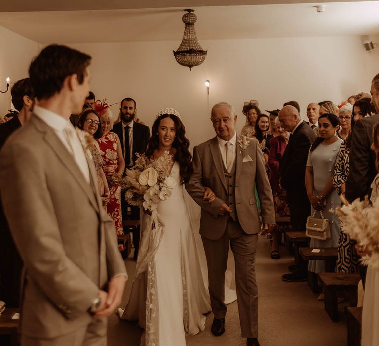 Father of the bride in neutral three piece suit walks the bride down the aisle for her boho luxe wedding at Aswarby Rectory 