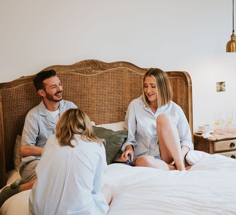 Bridesmaids & Man of Honour sit on bed in blue pyjamas on the morning of wedding 