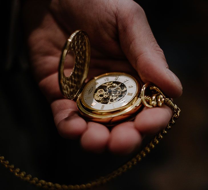 Groom holds gold pocket watch on the morning of his wedding day