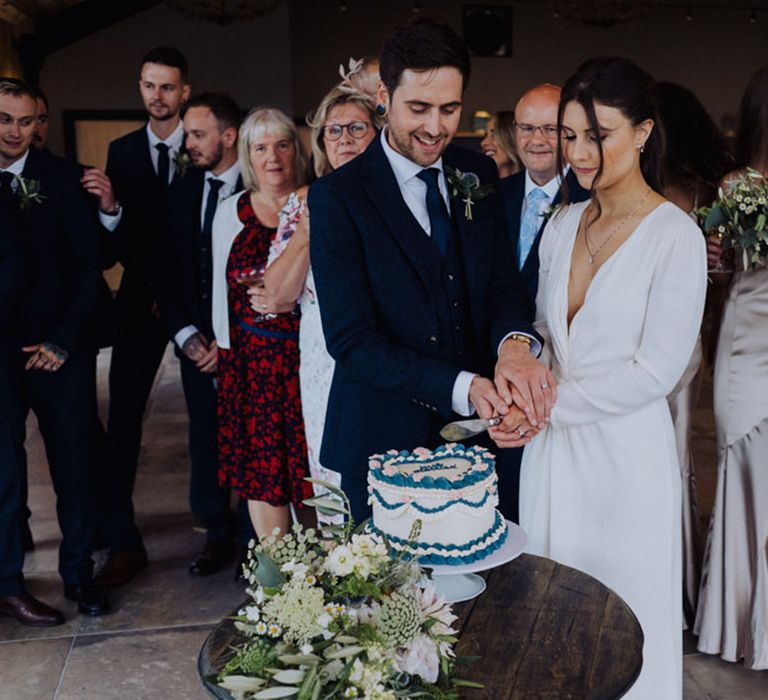 Bride and groom cut their heart shaped retro iced wedding cake 