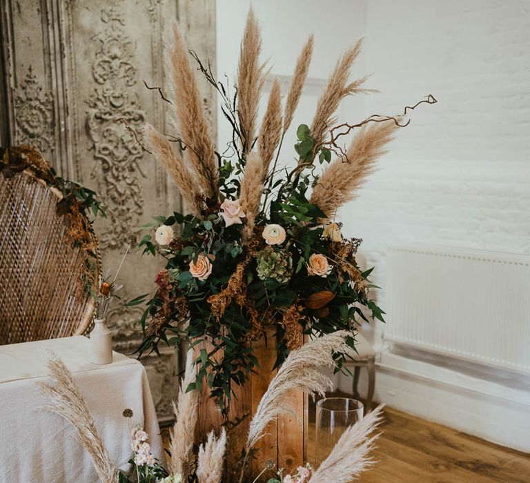 Pink, white and orange wedding flowers with pampas grass and white pillar candles in hurricane vases 