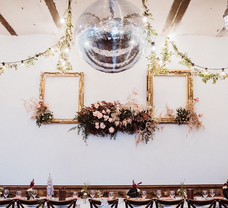 Clapton Country Club wedding venue decorated with foliage, pink flowers and dried grass and a disco ball 