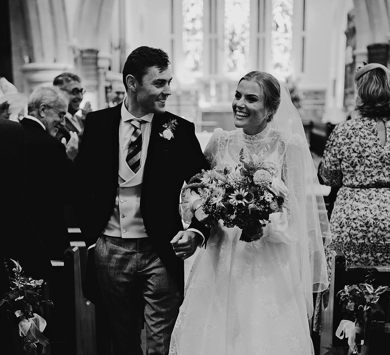 Bride and groom walk back down the aisle as a married couple after their church wedding ceremony 