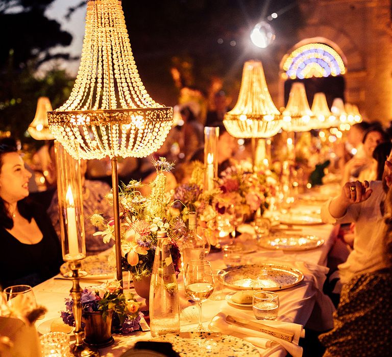 Lit up chandelier installations over the banquet tables at the wedding reception 