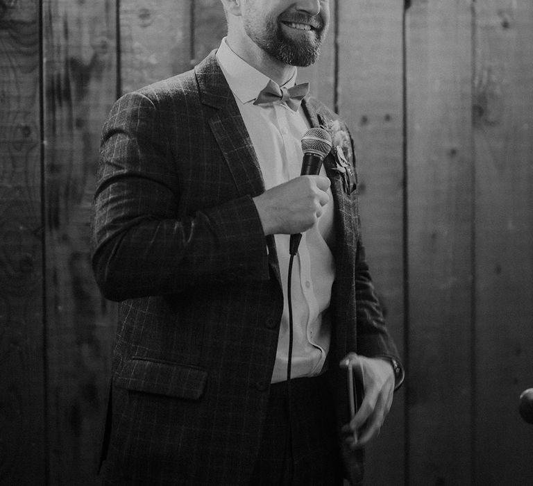 Groom stands smiling as he delivers his wedding speech 