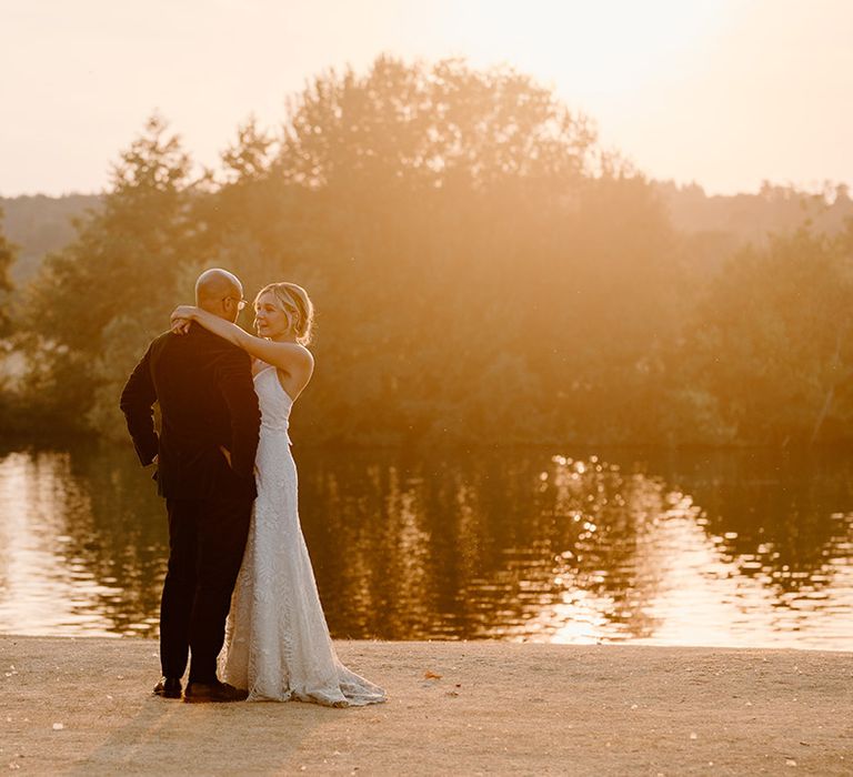 Bride & groom embrace outdoors by the River Thames during golden hour portraits 