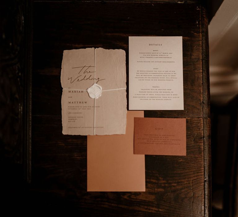 Red, orange, white, and beige flatlay of wedding stationery with a wax seal 