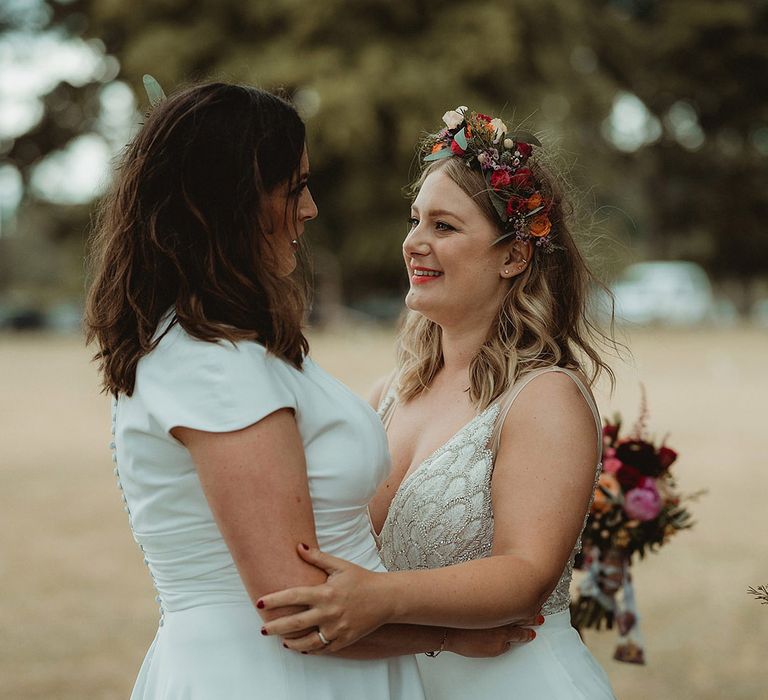 Brides gaze into each other's eyes as they pose for their couple portraits 