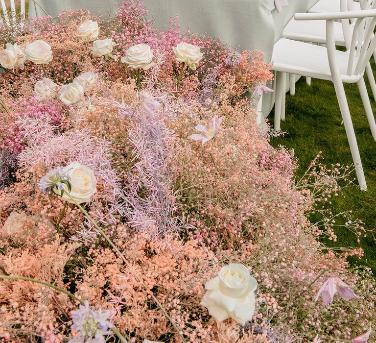 Pastel wedding flower arrangements for luxury outdoor wedding with roses and gypsophila in vases for the table decor and sitting on the floor next to the table 