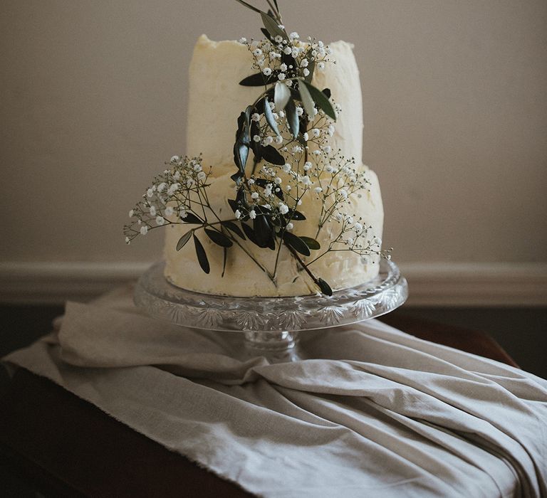 Two tier white wedding cake complete with floral decor and rustic design