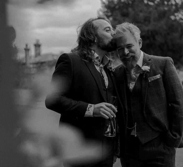 Grooms embrace in black & white image during couples portraits outdoors for botanical wedding