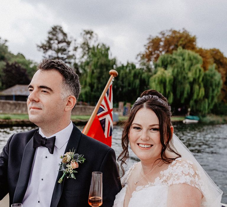 The bride and groom enjoy their boat ride around Henley on Thames for their traditional wedding enjoying some wine 