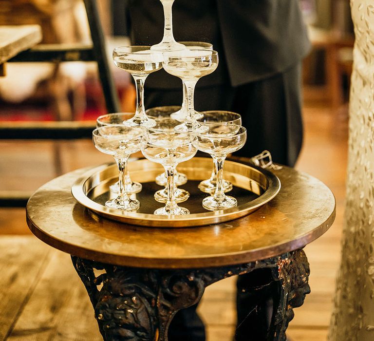 Bride & groom pour champagne into champagne tower during rustic wedding reception 