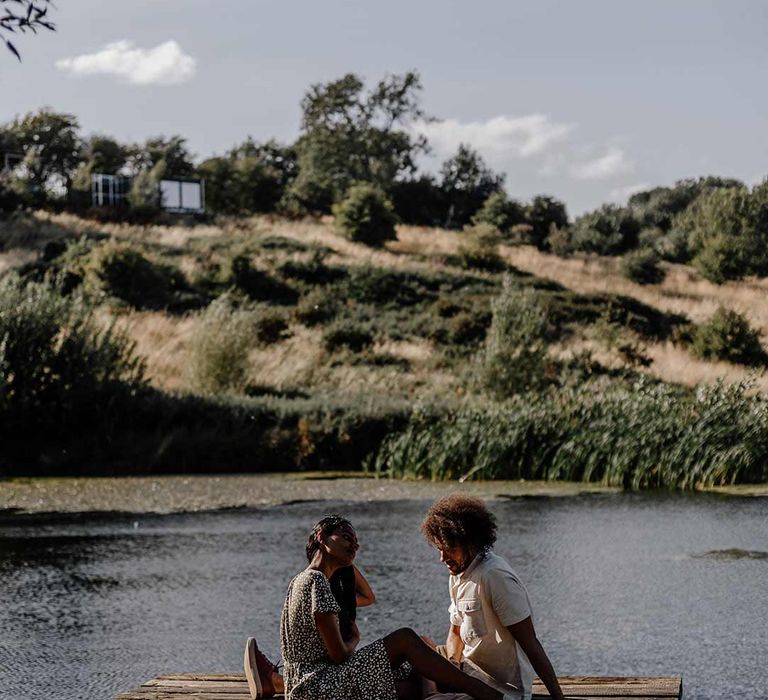 Bride and groom sitting at the end of a wooden pier next to a lake for Prezola wedding honeymoon 