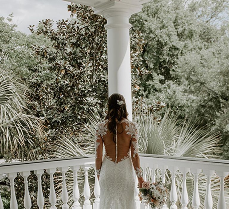 The bride wears an elegant mermaid wedding dress with an illusion button back 