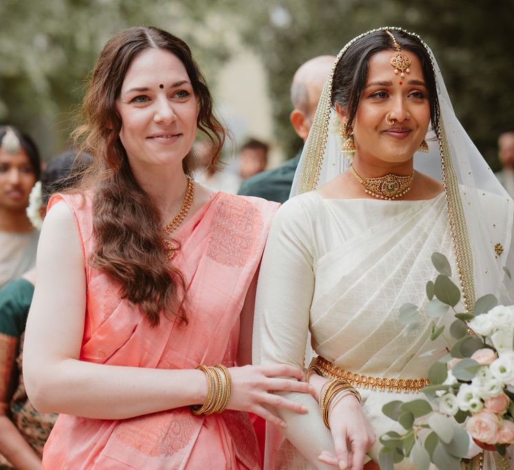 South Asian bride in a cream Lehenga walking down the aisle 