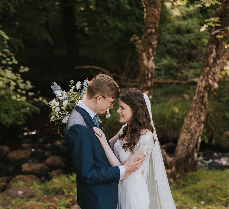 Badgers Holt rustic marquee wedding with the bride and groom posing together in a woodland surrounded by daisies 