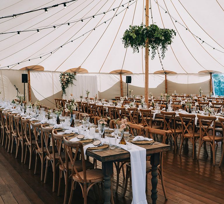 Marquee wedding reception at Willow Grange Farm with long banquet tables decorated with white tablecloths, wicker placemats, and wood slice place names 