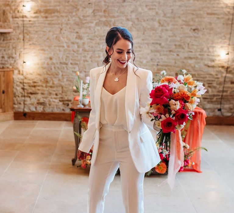 Bride in white bridal suit with closed toe bright green wedding heels holding large seasonal flower bridal bouquet at Merriscourt wedding venue