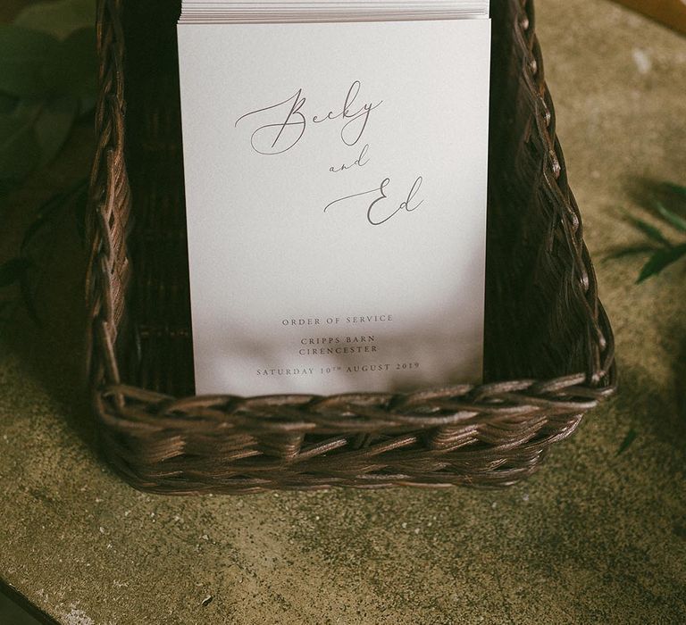 Brown wicker basket full of the order of service booklets for a church wedding ceremony 