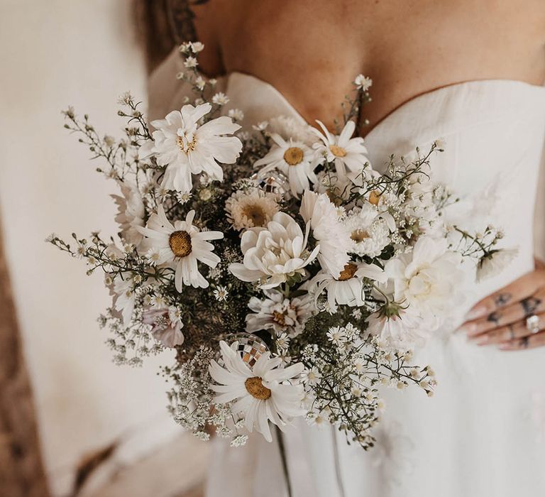 Bride holding white flower wedding bouquet with daisies and wildflowers 