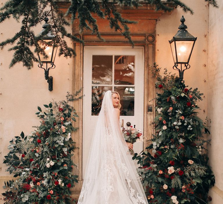 Bride wearing embellished lace wedding with embroidered cathedral length veil walking into Lincolnshire wedding venue 