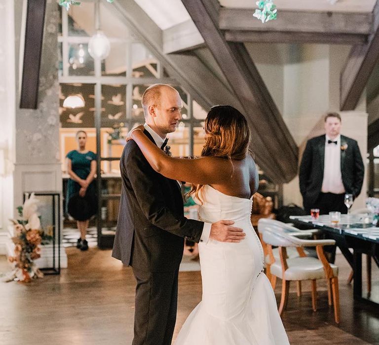 Bride in fitted mermaid wedding dress dancing with groom at their wedding reception 