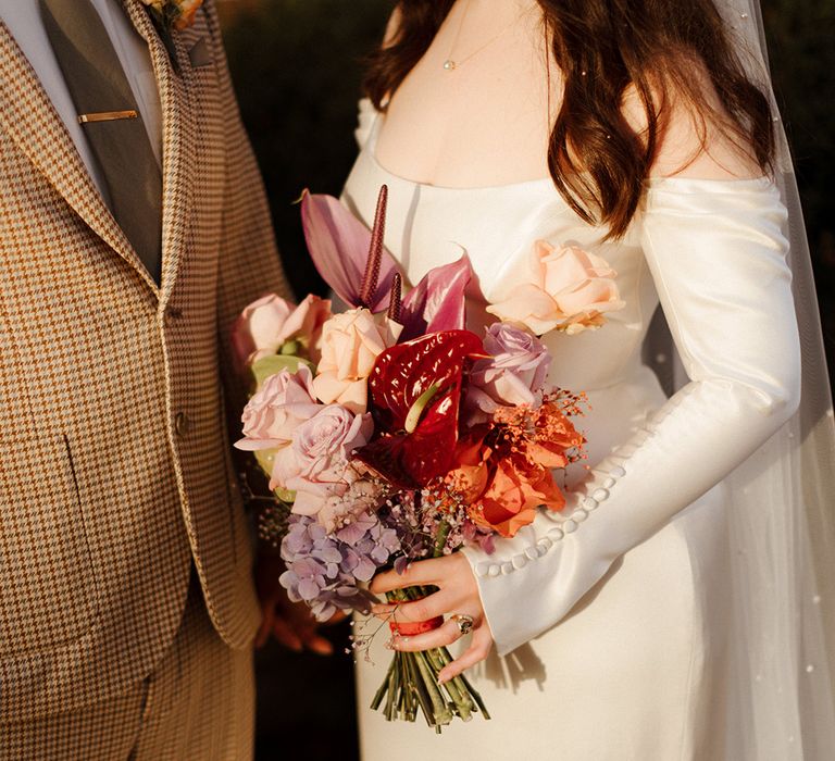 Bride holding pastel colourful wedding bouquet with anthuriums and roses 