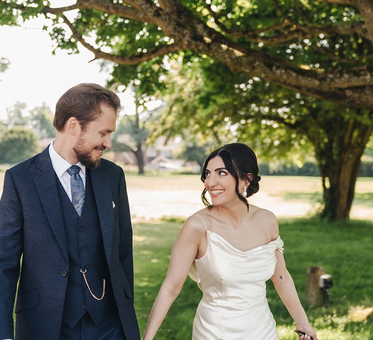 Groom in three piece navy wedding suit with the bride in a satin wedding dress 