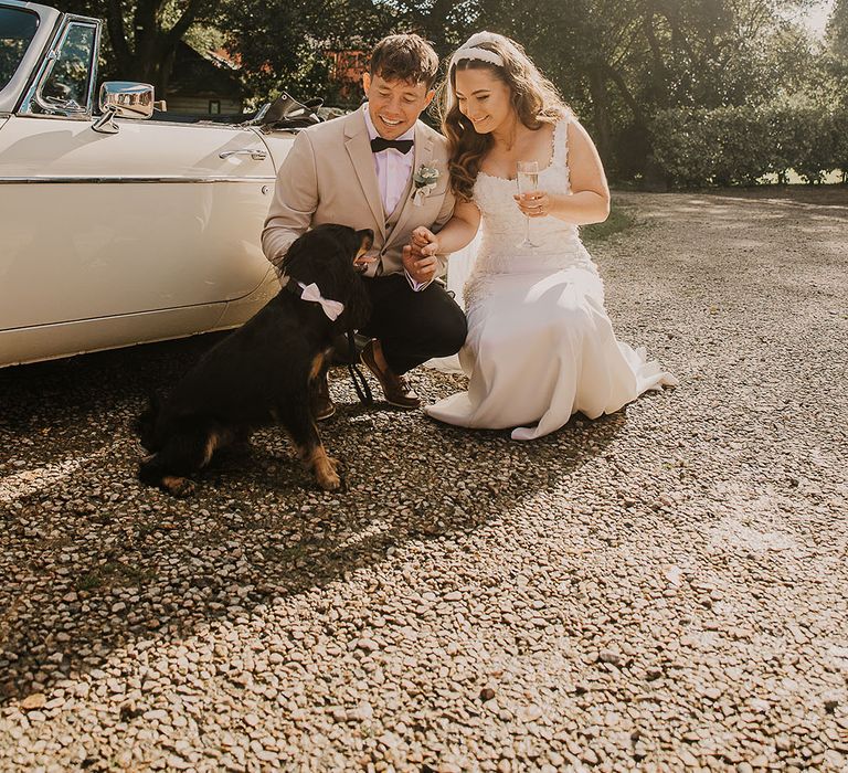 The bride and groom with their pet dog wearing a ribbon collar 