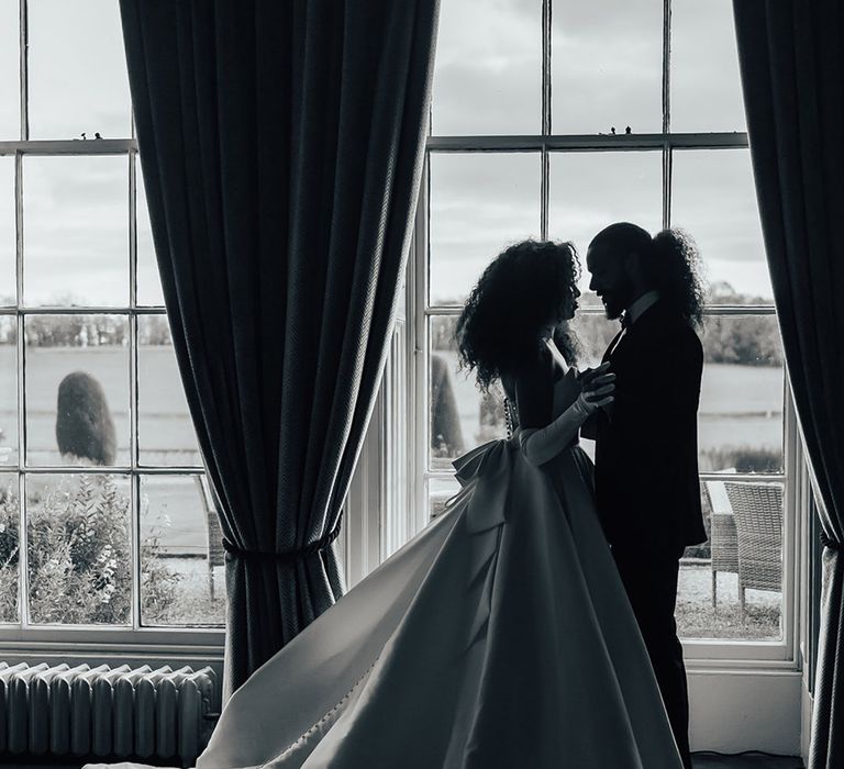 Bride and groom pose in front of the window for couple wedding photo 