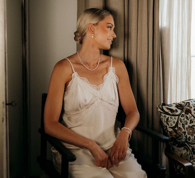 Bride getting ready for the wedding wearing white satin pyjamas 