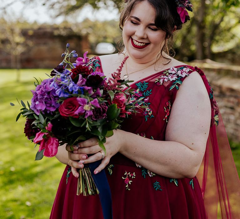 Bride wearing red embroidered wedding dress with bright wedding bouquet 