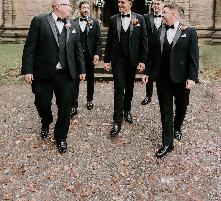 The groom and groomsmen walk together outside of the church at the Sheffield wedding 