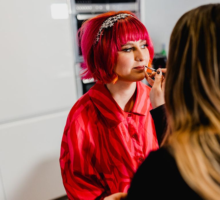 Bride with colourful pink hair colour sitting to get her makeup done 