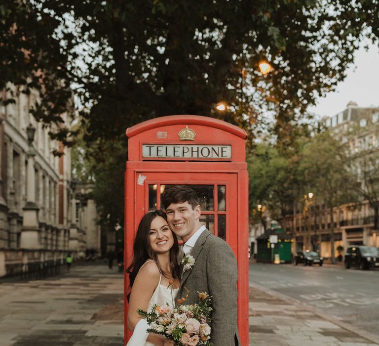 Bride and groom portrait next to a red telephone box in South Kensington 