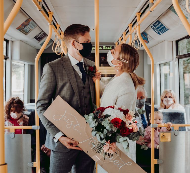 Bride and groom wearing PPE travelling on a tram 