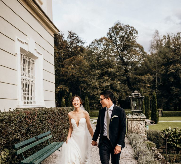 Portrait of the bride and groom walking through the wedding venue grounds by Candida & Max Jan Photography